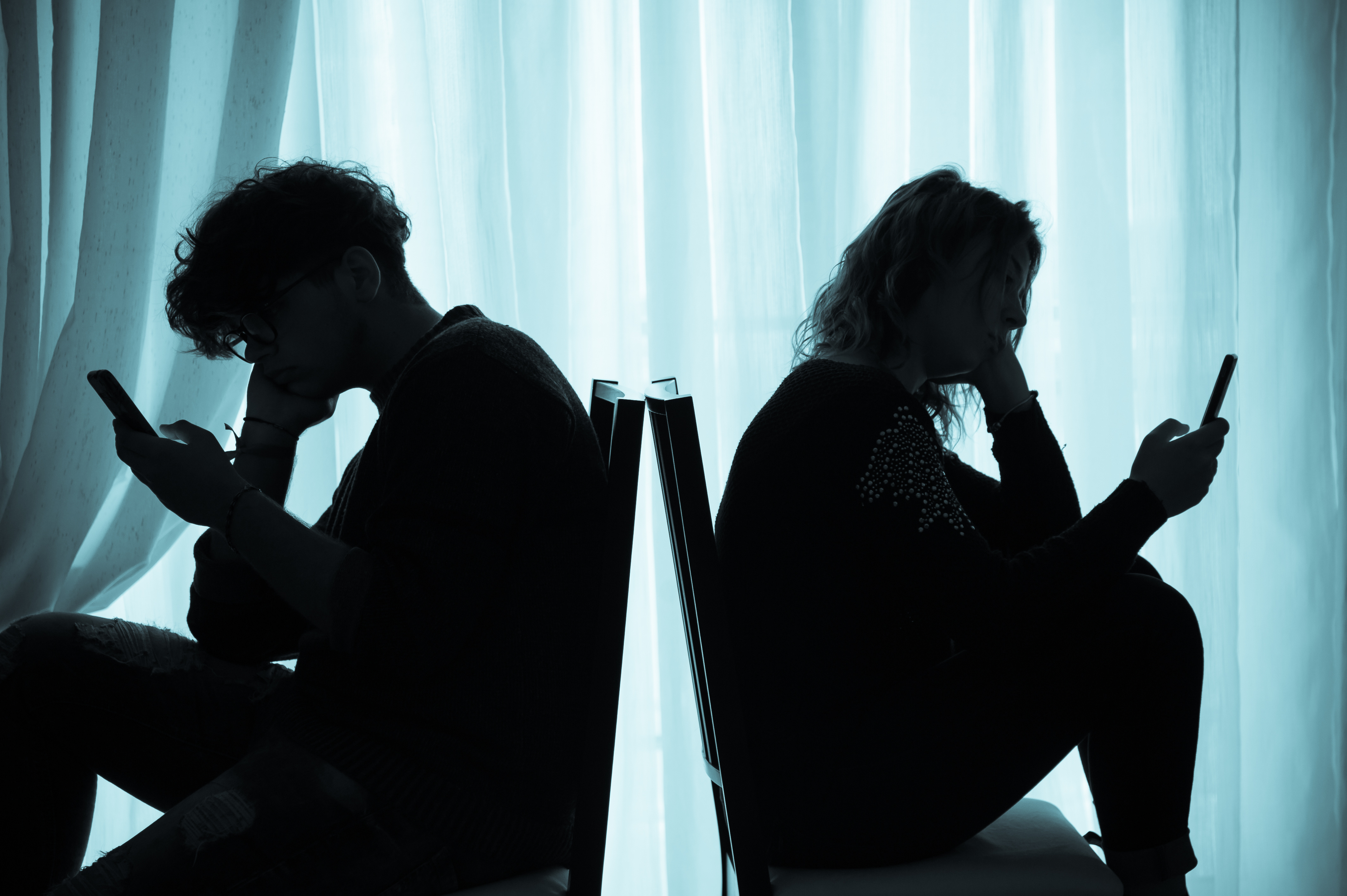 silhouette of man and woman using smartphones