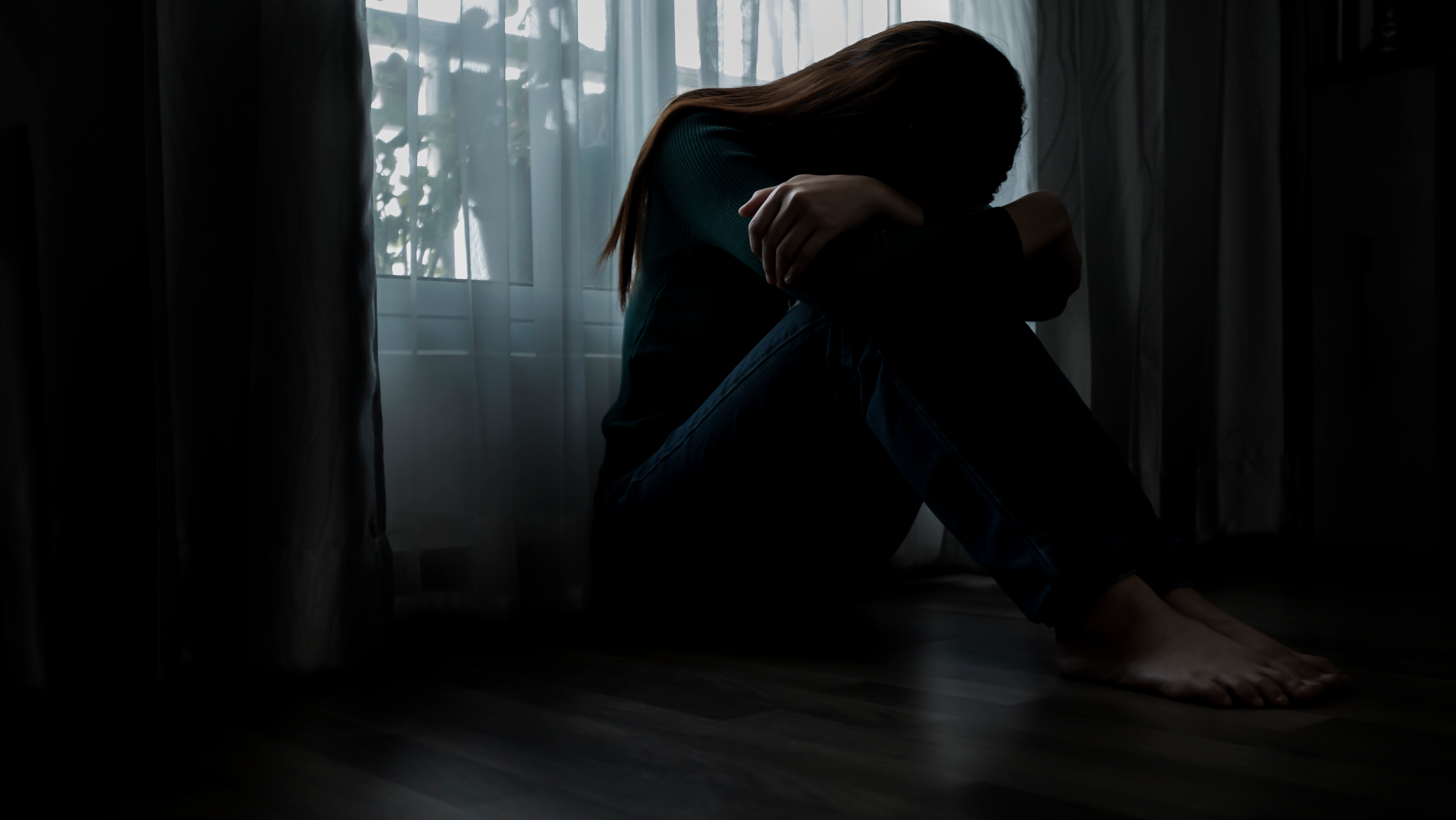 women sitting on the ground in a dark room with her head down