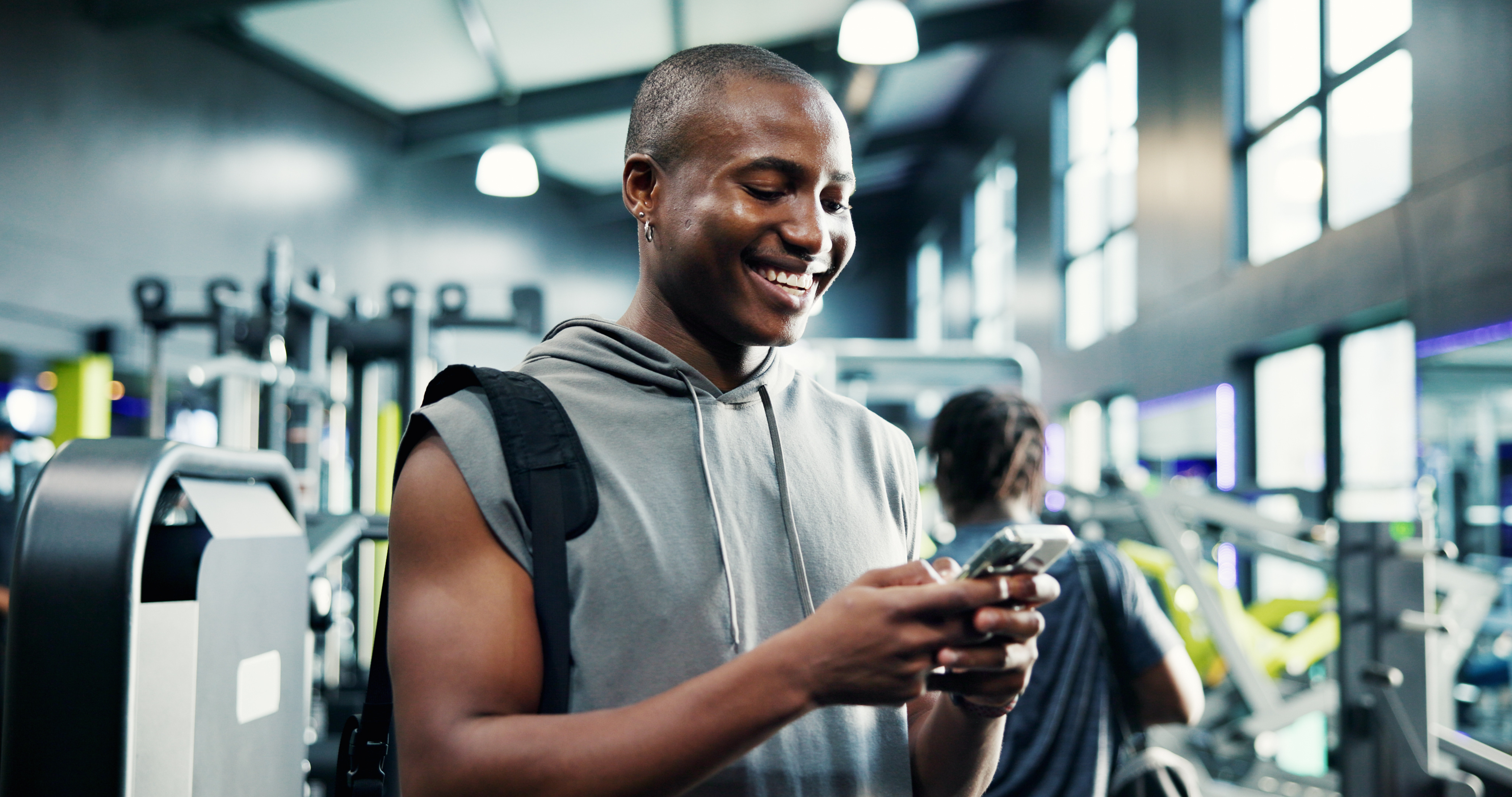Man smiling in gym using smartphone