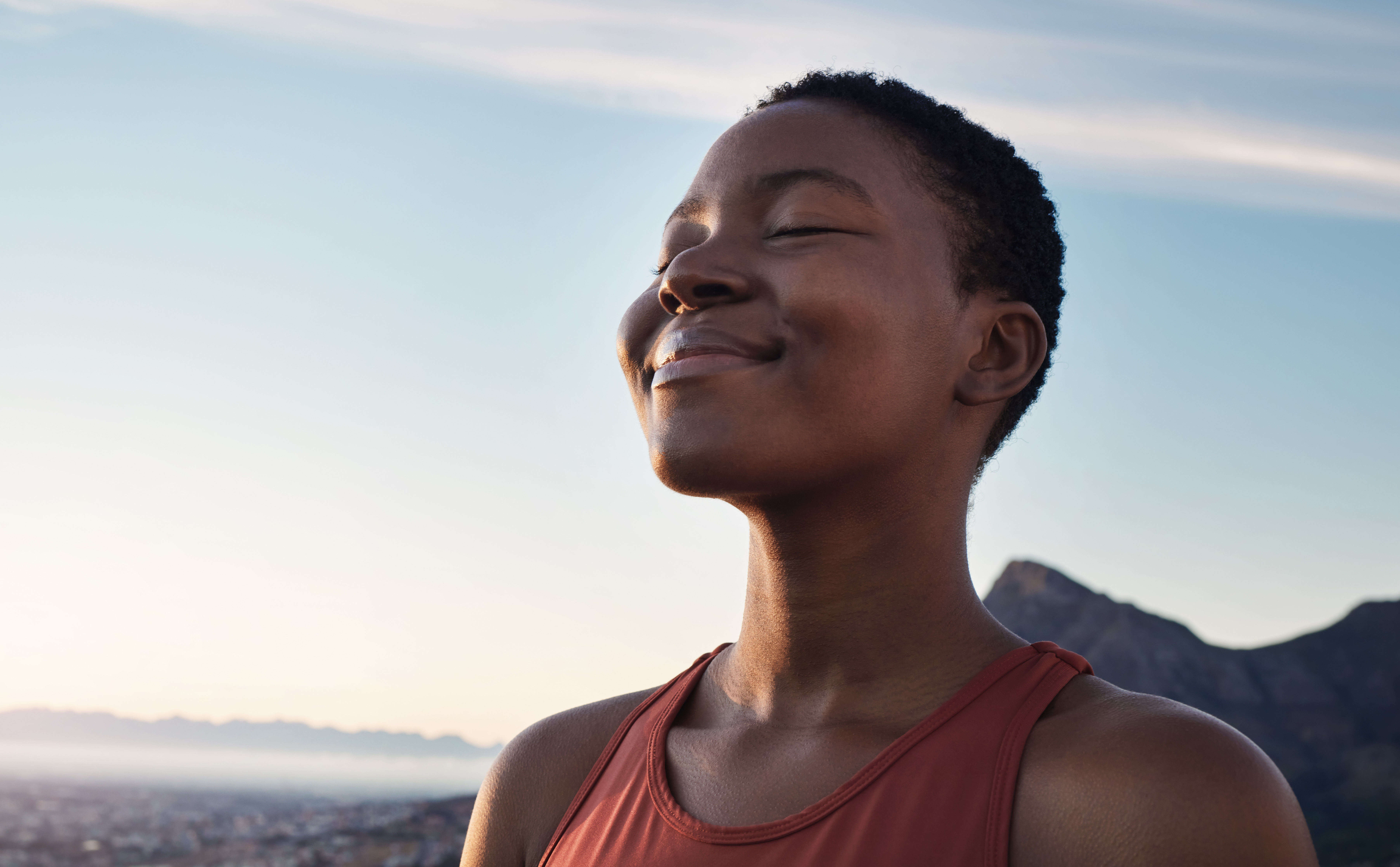 Woman outside smiling with eyes closed enjoying nature