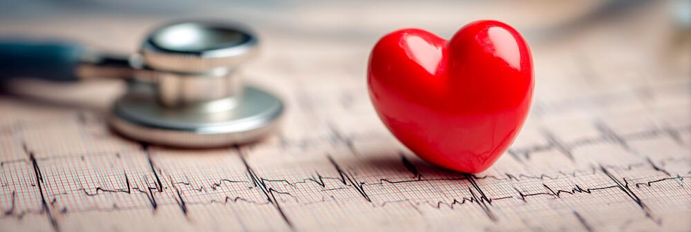 Electrocardiogram reading with a red plastic heart and stethoscope