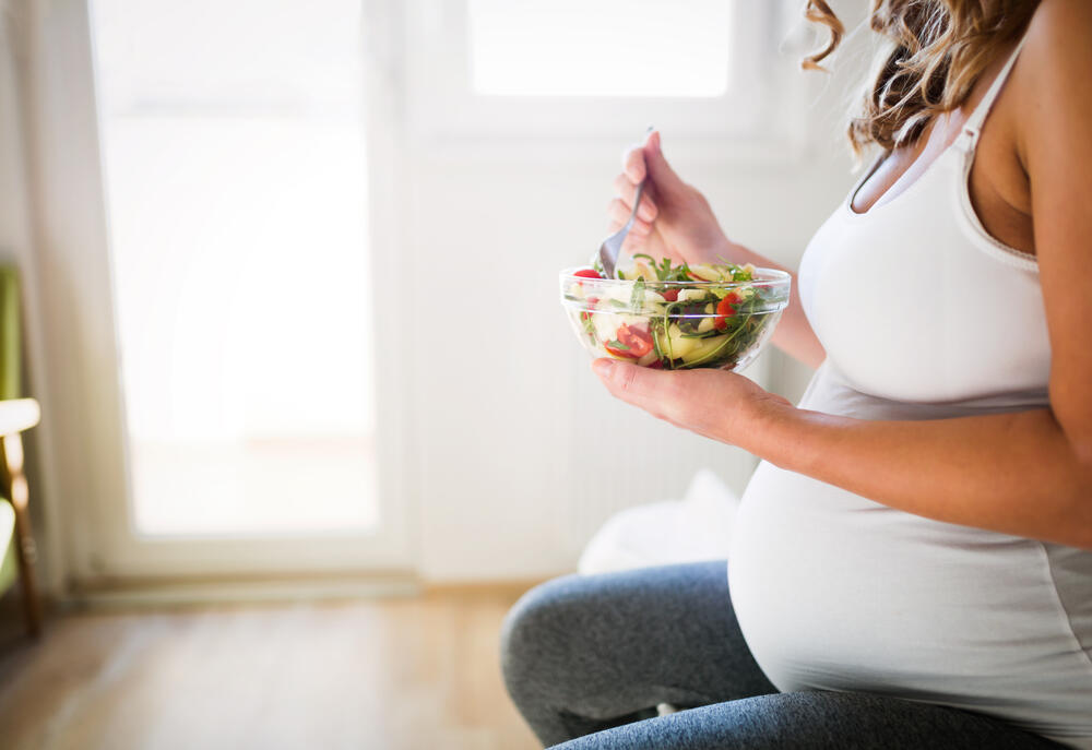 pregnant woman eating salad
