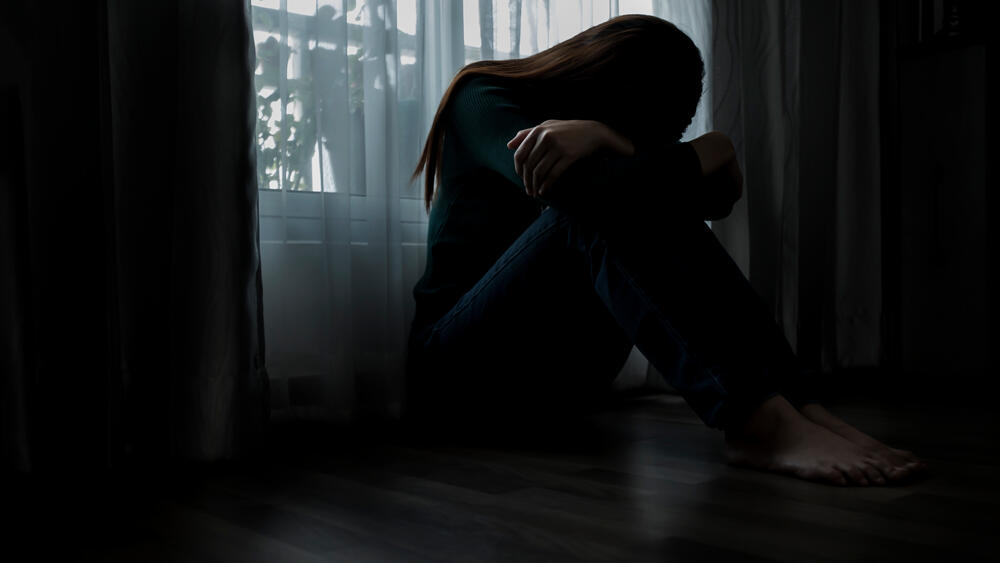 women sitting on the ground in a dark room with her head down