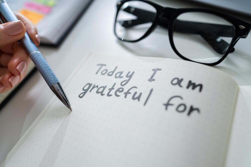 Person writing in journal the statement "Today I am grateful for"